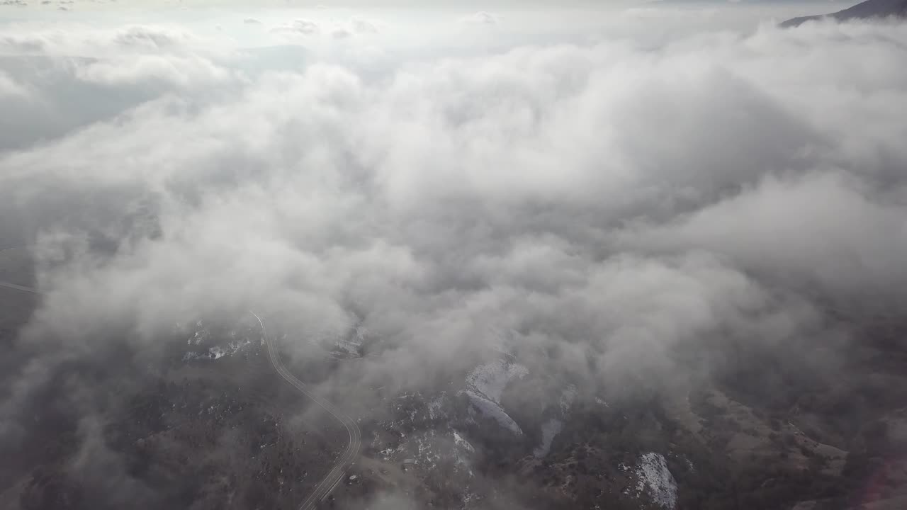 Gliding above the clouds looking down on a snowy mountain range