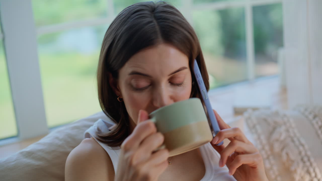 Closeup lady calling cellphone drinking tea at cozy home. Portrait smiling woman