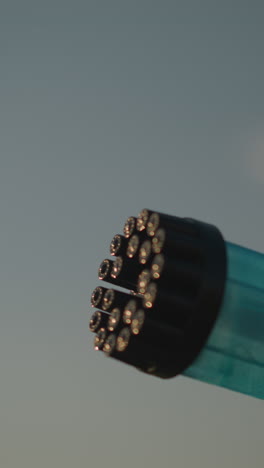 close-up of a plastic bubble gun releasing a stream of colorful bubbles under a clear sky. the vibrant bubbles catch the light, creating a magical and playful scene