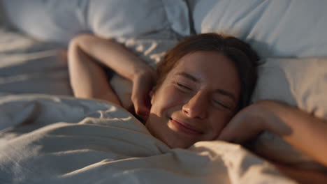 happy woman stretching bed in sunlight closeup. carefree smiling girl waking up