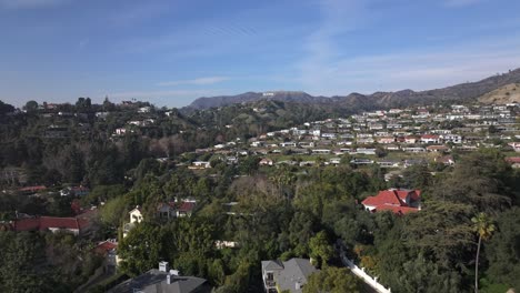 neighborhood of homes on clear day in los angeles, hollywood sign in distance, aerial view