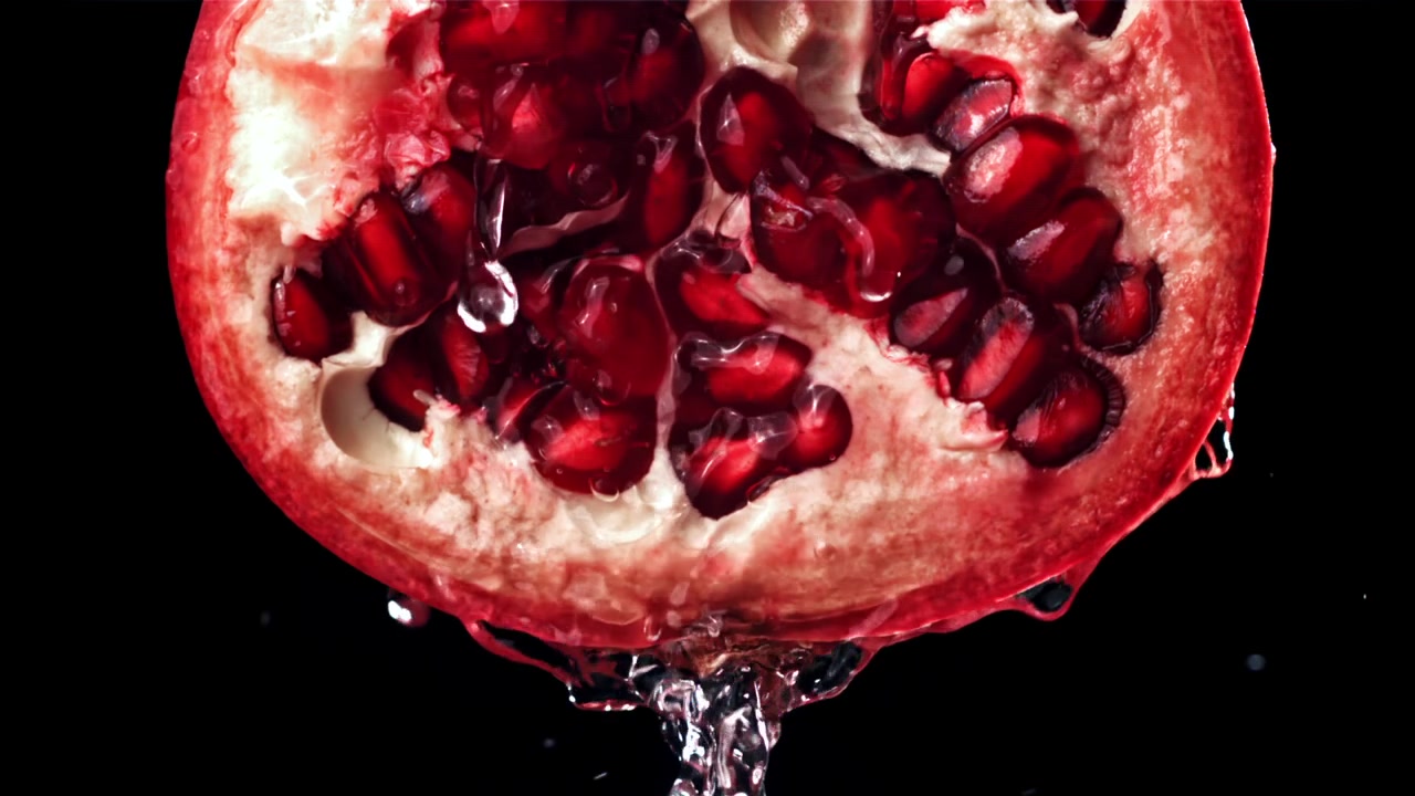 Slowmotion vand sprøjter på et frisk halvt granatæble