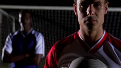 porträt eines selbstbewussten fußballspielers, der den ball mit einem rivalisierenden athleten hält 4k