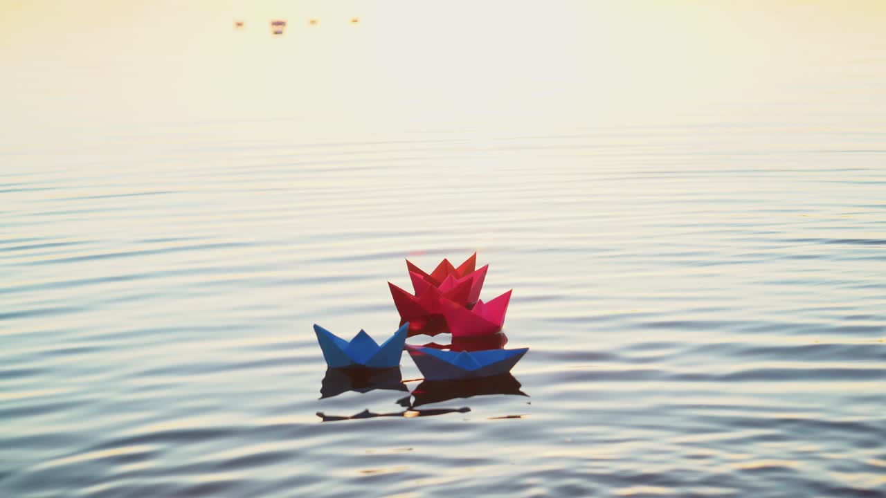 Toy paper boats on the surface water at sunset. Colored paper ships in the water