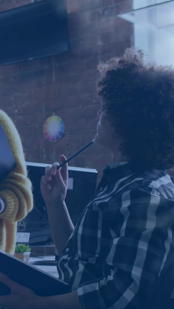 Vertical video: Designer glancing screen, adjusting tablet, color wheel over tablet guiding design