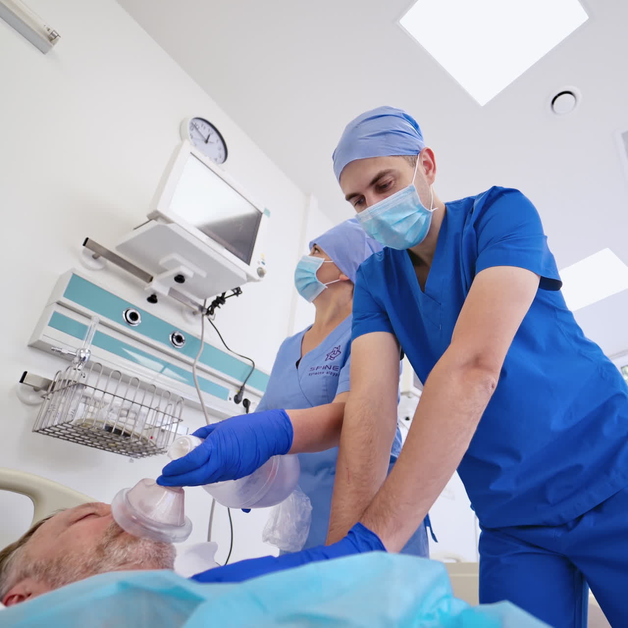 Doctor trying to save dying patient in the emergency room background. Specialist male and a nurse giving resuscitation to an old man patient in clinic.