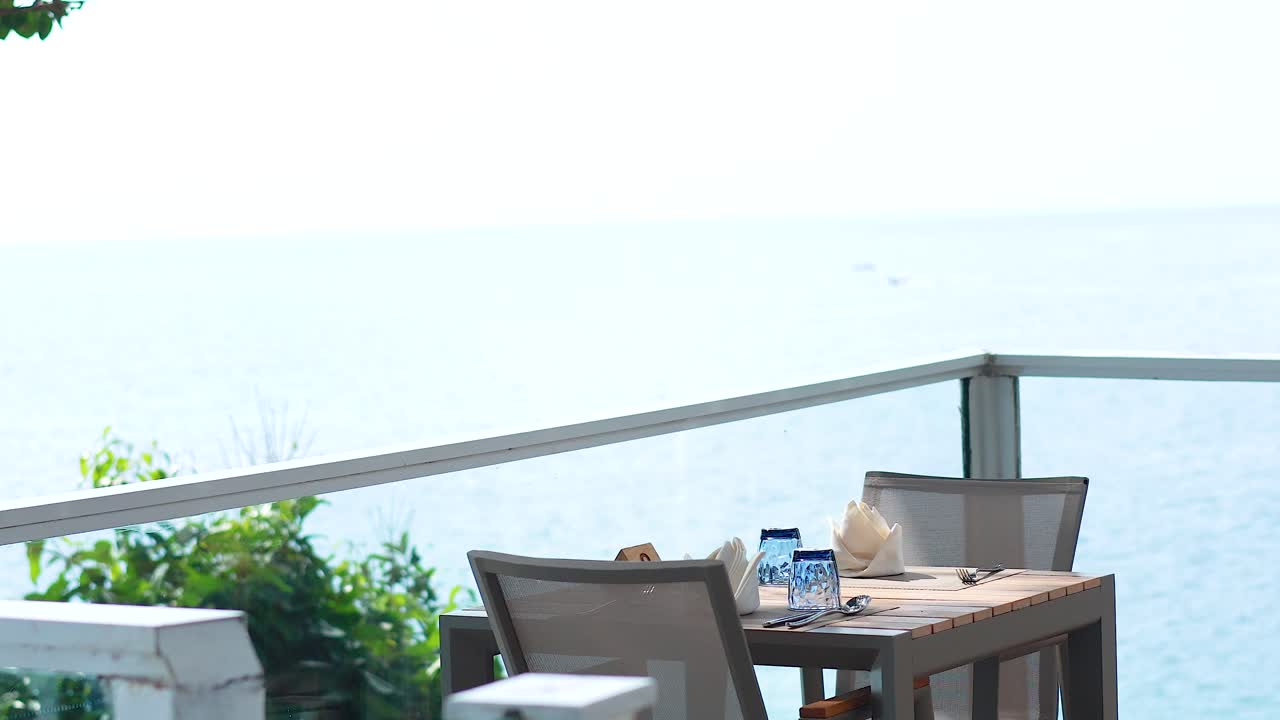 A serene dining setup overlooking the ocean, captured in bright daylight with minimal movement