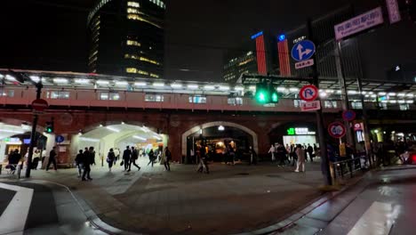 night street scene in tokyo with people crossing, tall buildings, and bright city lights