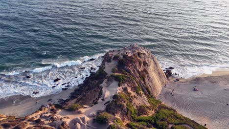 aerial orbits rock cliff outcrop at malibu beach on california pacific