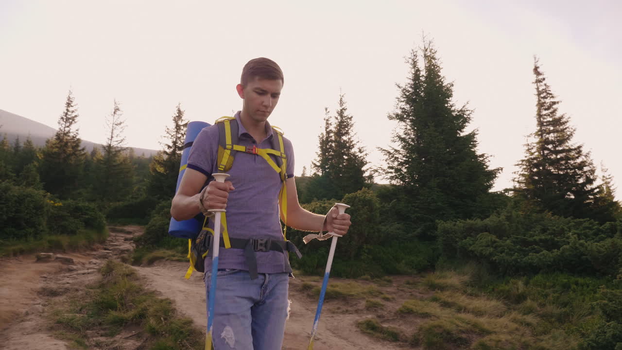 un joven turista sube a la montaña usa bastones de trekking en el contexto de un pintoresco s
