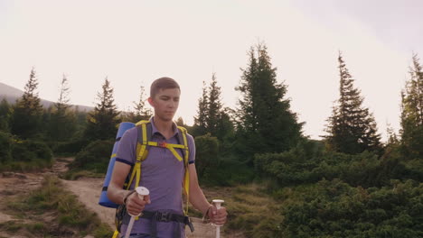 a young tourist rises up the mountain uses trekking sticks against the background of a picturesque s