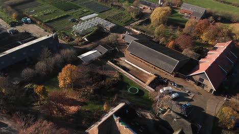 Aerial-view-of-behind-a-biological-dynamic-farm-in-The-Netherlands-with-a-diversity-of-buildings,-barns,-greenhouses,-crops-and-pasture-lands