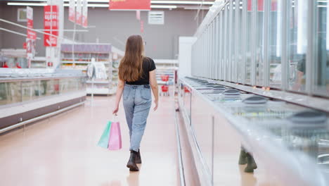 back view of lady walking through a mall holding shopping bags with sleek cabinets reflecting the surrounding area, showcasing a vibrant shopping environment with hanging signpost