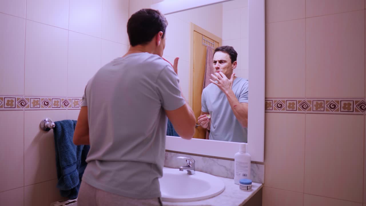 Man applying cocoa lip balm in bathroom mirror