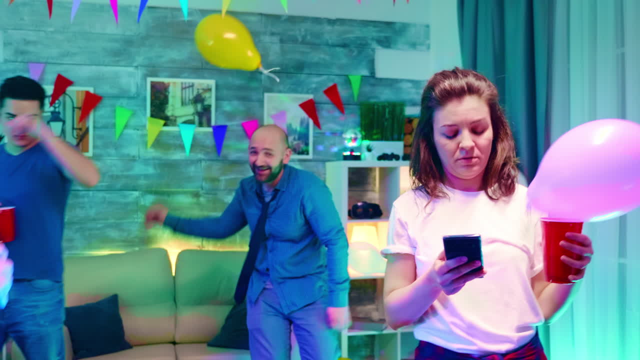 chica aburrida enviando mensajes de texto en su teléfono inteligente en la fiesta de sus amigos