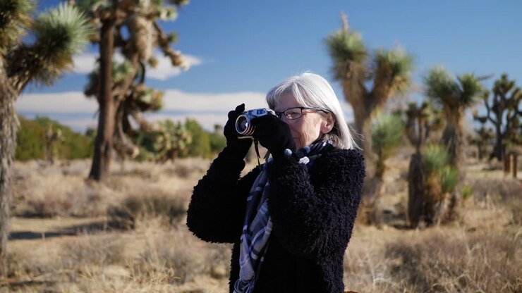 An adult woman photographer taking pictures with her old fashioned film camera in a desert wildlife landscape
