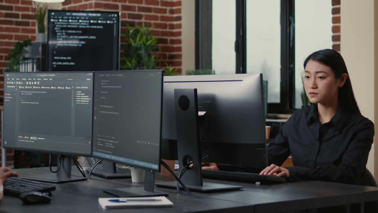 Two focused coders facing each other writing code in software development office