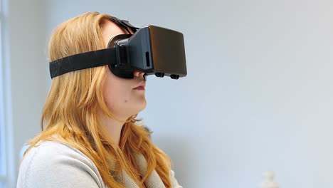 Woman-using-virtual-reality-headset-while-working-on-laptop