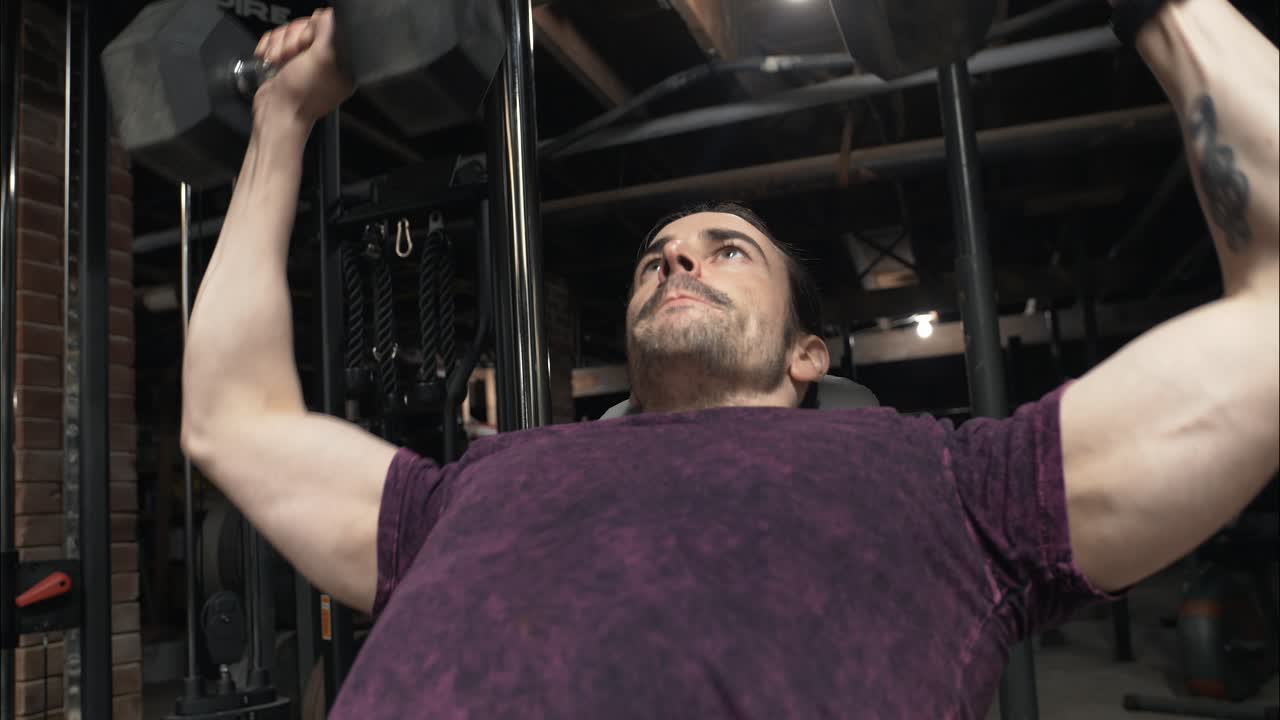 Man weightlifting, working out, exercising with dumbells in home gym.