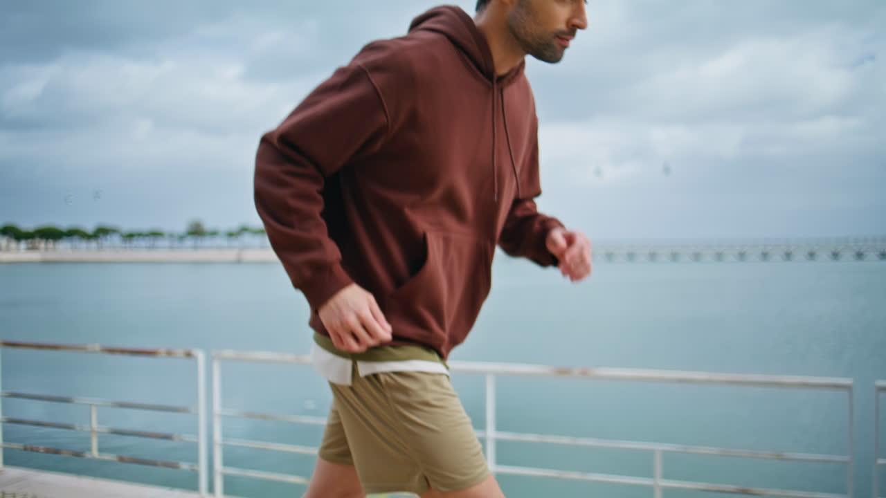 Closeup athlete body warming up before sprinting. Fit man running riverside