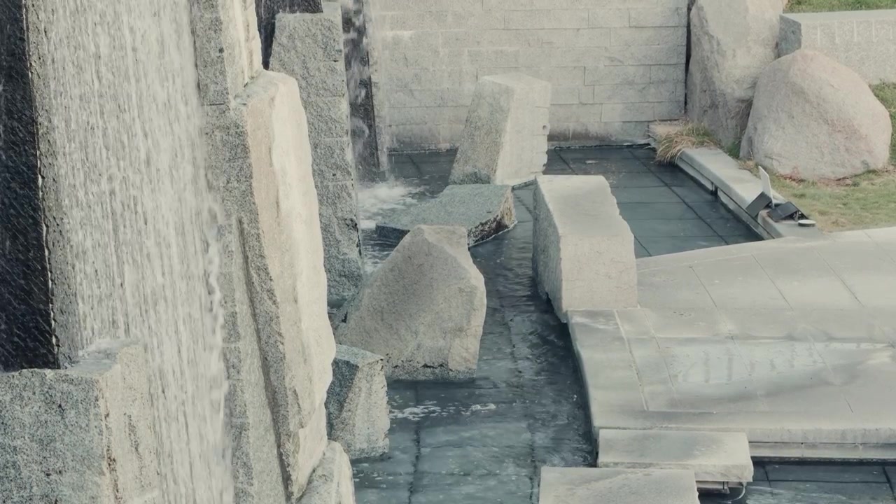 Static downward view of flowing water through a decorative stone fountain.