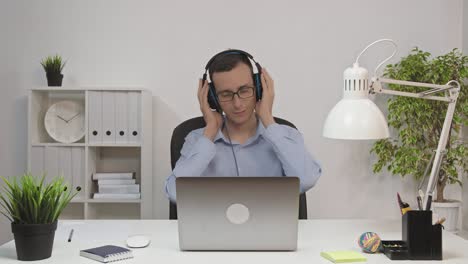 relaxed businessman singing and listening music using headphones at office