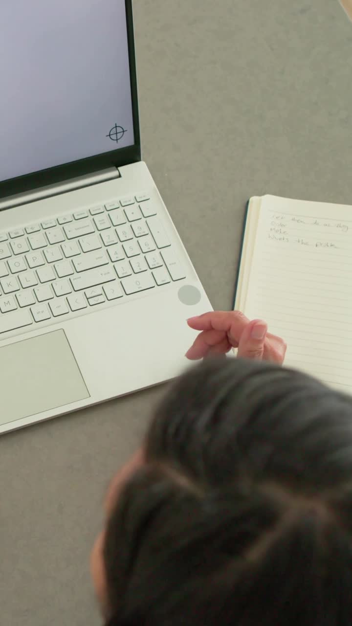 Vertical video: Gesturing woman reaching for laptop at home, checking notes and phone, copy space