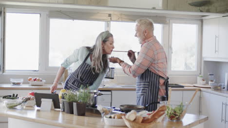 middle aged caucasian couple preparing meal, cooking together in kitchen at home, slow motion