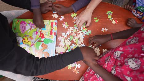 african kids doing a puzzle with a white volunteer at the orphanage