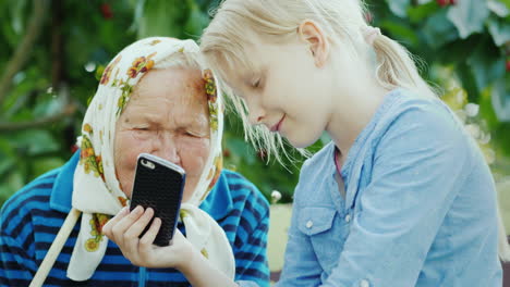 La-Niña-Muestra-Fotos-De-La-Abuela-En-Su-Teléfono-Inteligente-Comunión-De-Generaciones-Concepto-4k-Video