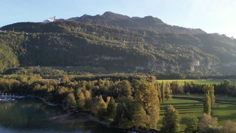 An-aerial-view-of-the-Walensee-lake-and-the-surrounding-green,-lush-mountain-hills-can-be-seen-against-a-sunny-and-blue-sky