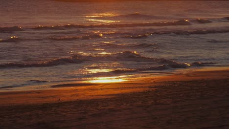 Ocean-Waves-on-sandy-beach,-sunrise-reflecting-in-water,-slow-motion,-mediterranean-coast,-spain