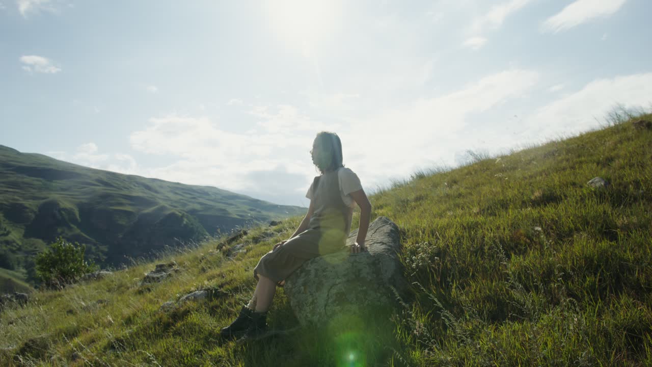 산의 풍경에서 바위 위에 앉아 있는 여자