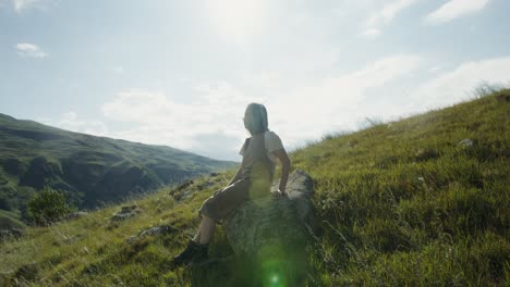 woman sitting on a rock in a mountain landscape