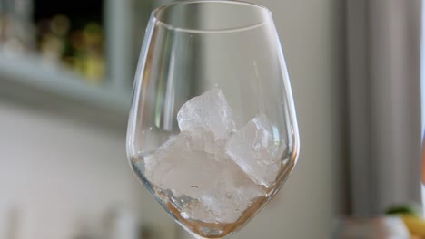 Mano-Dejando-Caer-Hielo-En-Una-Copa-De-Vino-En-Casa.-Concepto-De-Bebidas-Frías-Mano-Dejando-Caer-Hielo-En-Una-Copa-De-Vino-En-Casa