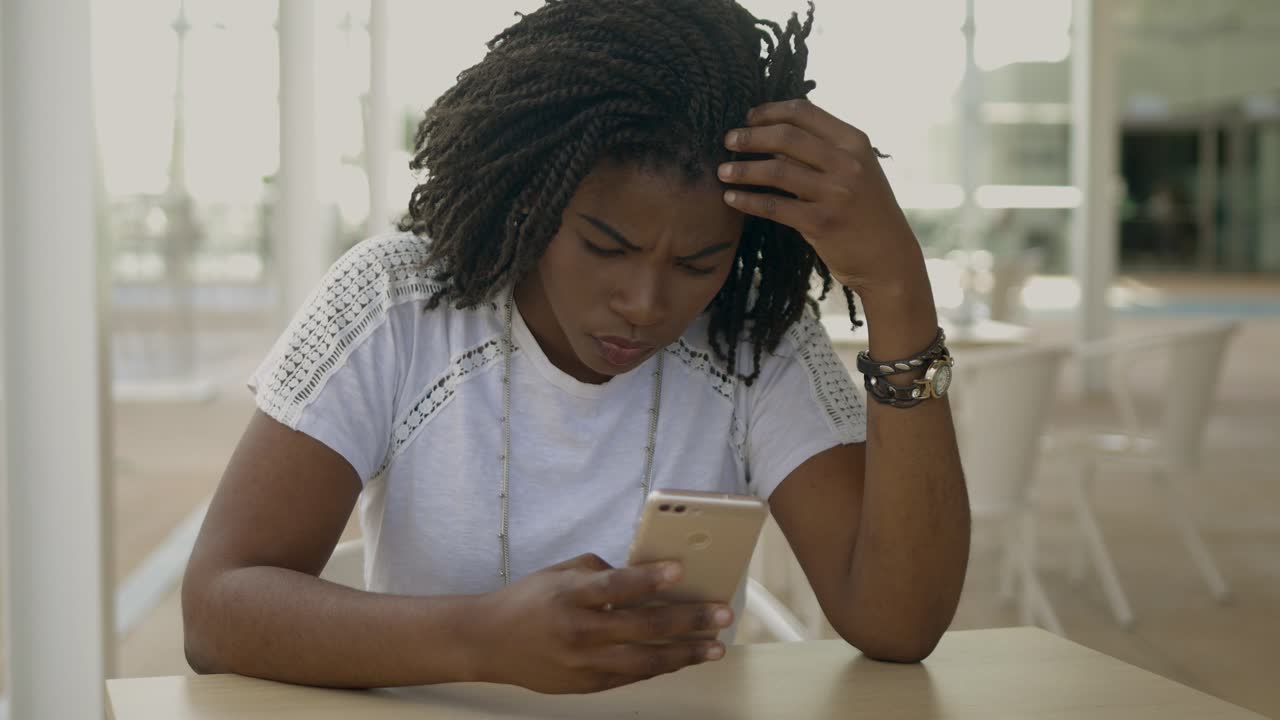 una donna afroamericana premurosa che usa lo smartphone.