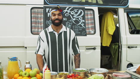 portrait of happy middle eastern salesman by food truck