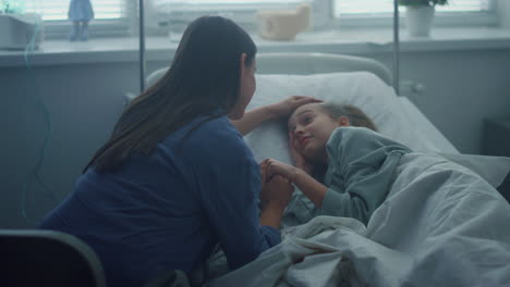 recovering child lying in bed near caring mother pediatric hospital unit.