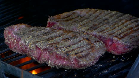 two thick and juicy rib eye steaks are covered as a grills lid is closed in