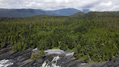 Disparo-Aéreo-En-Declive-Lento-Sobre-Las-Islas-De-Vancouver,-La-Salvaje-Y-Escarpada-Costa-Oeste,-Que-Revela-Una-Pequeña-Bahía-Y-Grandes-Olas-Rompiendo-Debajo