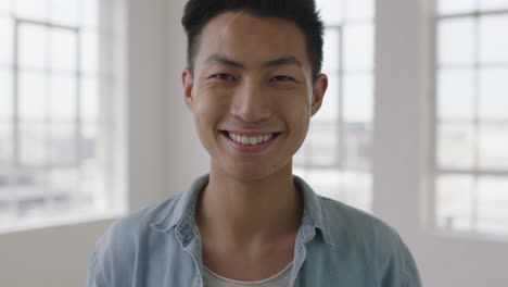 close-up-portrait-of-young-asian-man-laughing-cheerful-looking-at-camera-apartment-windows-background-slow-motion