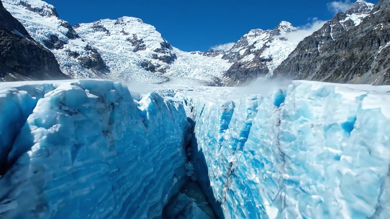 Impresionante paisaje glacial: Una vista panorámica de extensos campos de hielo y grietas glaciares bajo un cielo azul claro.