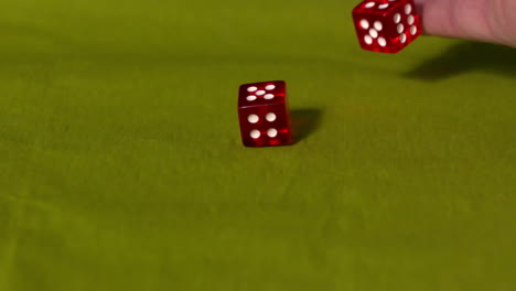 mano lanzando dos dados rojos en la mesa verde