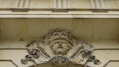 ornate stone carving of a man's head adorning a building facade