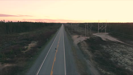 un tipo patina en un largo camino durante una puesta de sol de verano