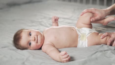 la pequeña niña acostada de espaldas recibe una carga de las manos de su madre