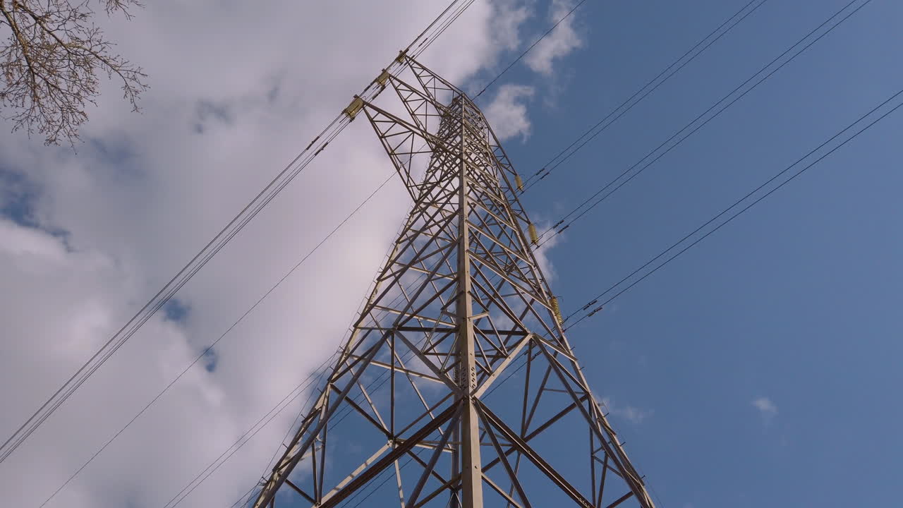 Electricity pylon in the middle of a farmers field with cables stretching across the blue sky and countryside