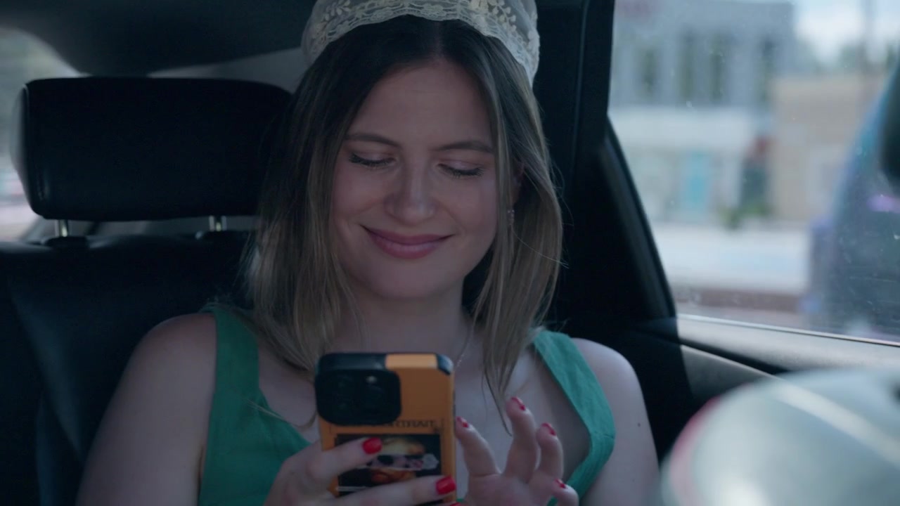 Giovane donna che usa lo smartphone sul sedile posteriore dell'auto