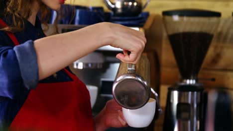 waitress pouring milk in coffee at counter