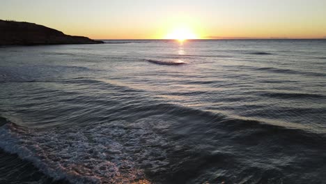 Beautiful-slow-motion-shot-flying-low-over-breaking-waves-during-sunset